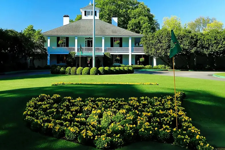 Azaleas in bloom framing the Augusta National Clubhouse at sunrise, spectators gathering along the pathways