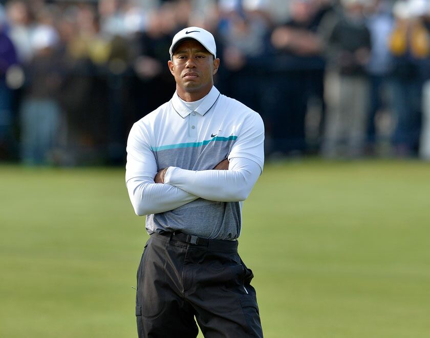 Golfer striking a long iron on a windswept links course during the Open Championship