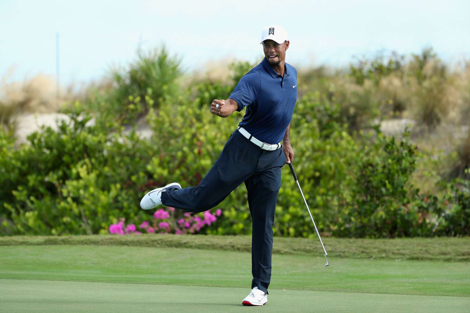 Golfer raising arms in a victory pose as an enthusiastic crowd cheers and cameras flash